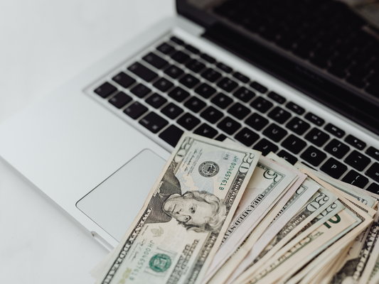 US dollar bills lying on a laptop keyboard