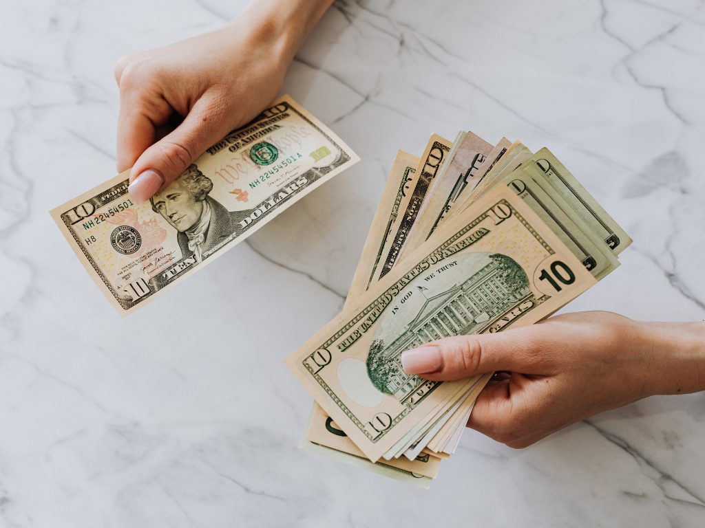 Hands counting ten dollar bills on a marble table